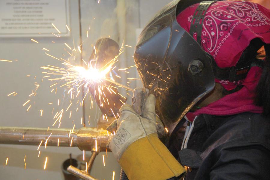 Welding student with sparks using welding torch